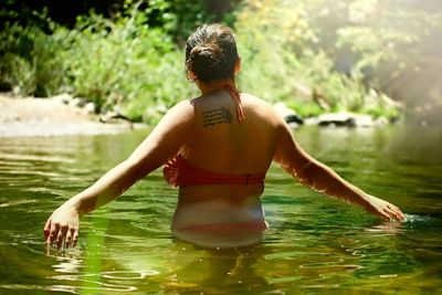 Rear view of shirtless man swimming in water