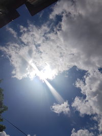 Low angle view of sunlight streaming through clouds