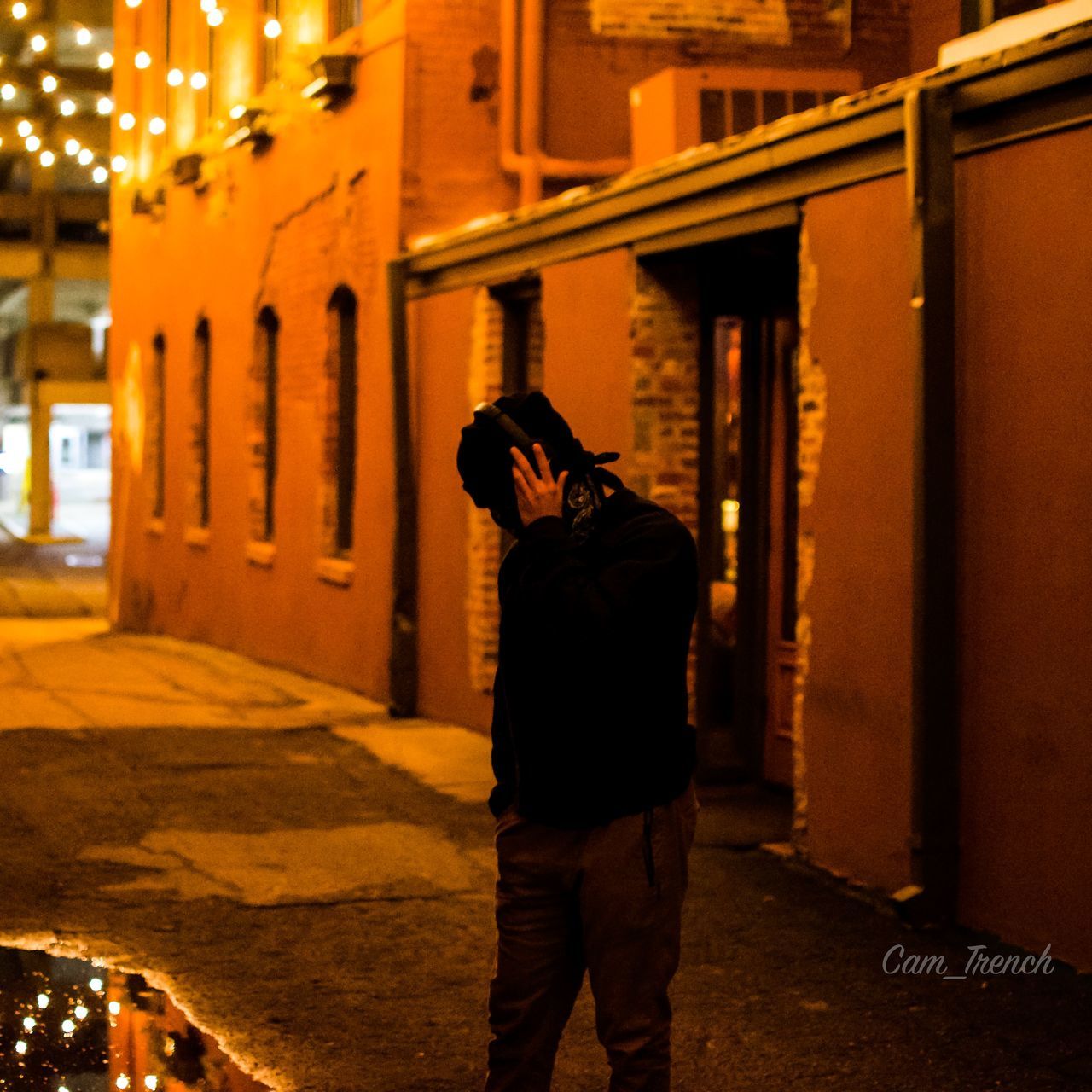 REAR VIEW OF MAN STANDING ON STREET IN CITY