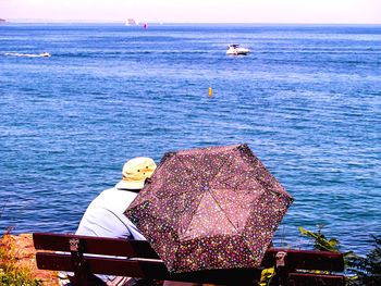 Man sitting in sea against sky