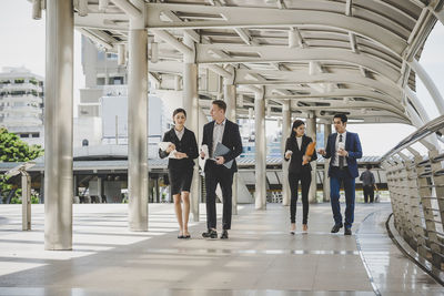 Business people talking while walking in office corridor