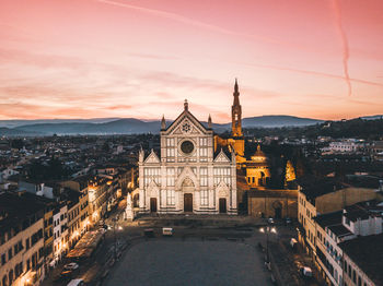 Illuminated buildings in city against sky at sunset