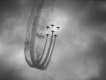 Low angle view of airshow against cloudy sky