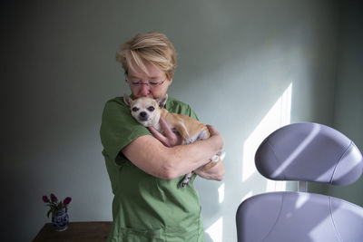 A medical worker holding and kissing her dog on the head