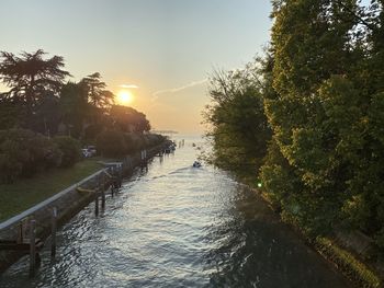 River amidst trees against sky during sunset