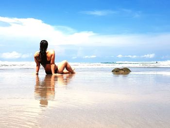 Rear view of woman on beach against sky