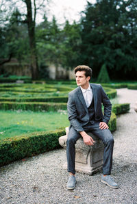 Portrait of young man sitting on footpath