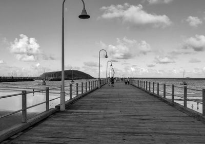 Street light on pier by sea against sky