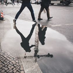 Reflection of men in puddle on street