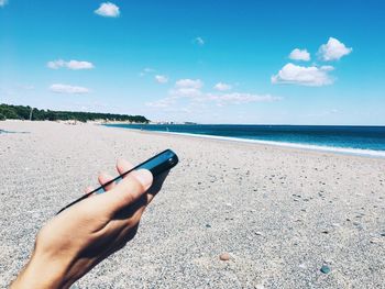 Cropped image of person holding blue sea against sky