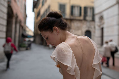 Rear view of woman looking down while walking on street in city