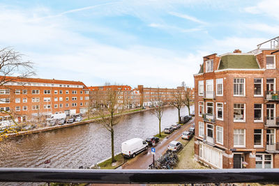 Canal amidst buildings in city against sky