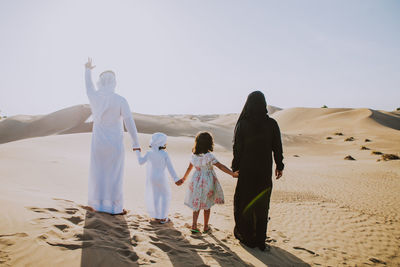 Rear view of women on beach against sky