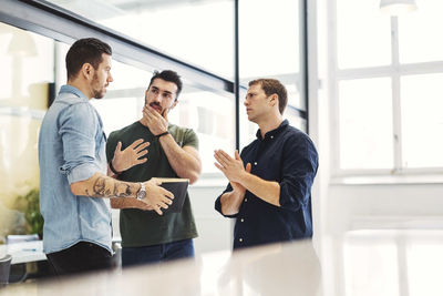 Businessman having discussion with male colleagues in office