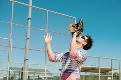 Low angle view of person wearing gloves against sky