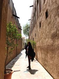 Full length of woman walking on footpath amidst buildings