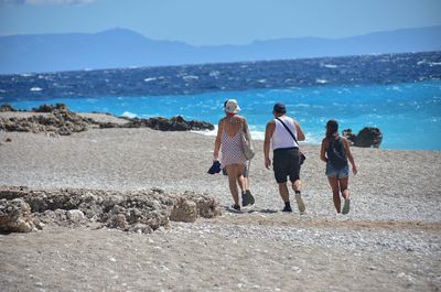 Rear view of people walking on beach