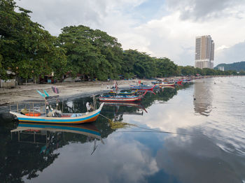 Boats moored on river in city against sky