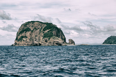 Rock formation in sea against sky