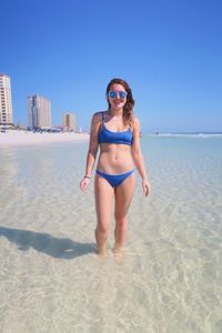 Portrait of young woman in bikini standing in water at beach