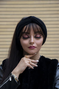 Portrait of young woman against wall