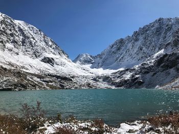 Scenic view of lake and snowcapped mountains against blue sky