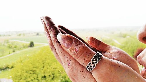 Close-up of hand feeding horse against sky