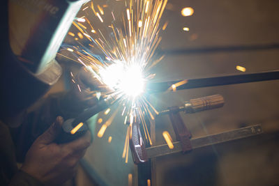 Cropped hand of man holding sparkler at night