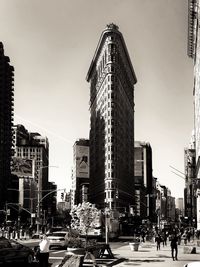 Cars on road by buildings against sky in city