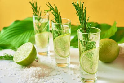 Drink with lime and rosemary on yellow background