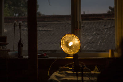 Close-up of illuminated light bulb against window
