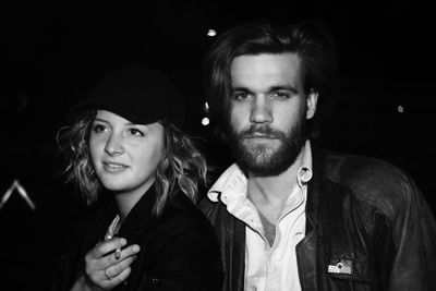 Man smoking cigarette while standing with man at night