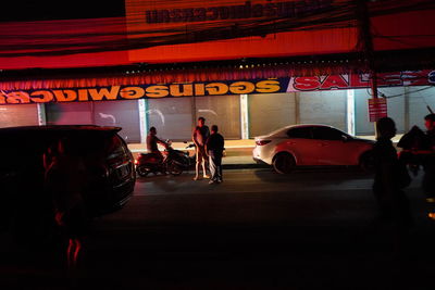 People walking on illuminated street at night