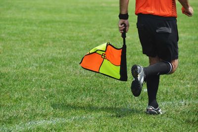 Low section of man with bag running on grass