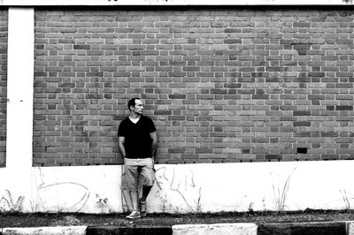 Young woman standing against brick wall