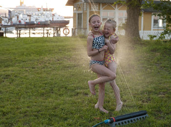 Girls playing with water sprinkler in garden