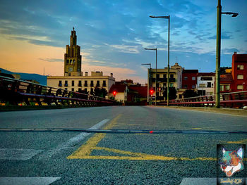 Road by buildings against sky in city