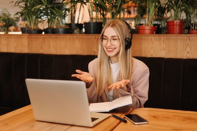 A smiling student wearing glasses and headphones works and studies online using wireless technology
