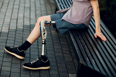 Low section of woman sitting on footpath