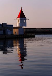 Building by sea against sky during sunset