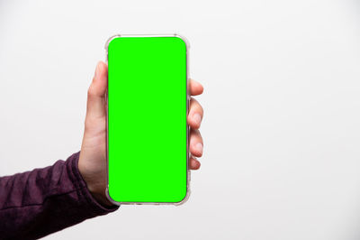 Cropped hand of person holding mobile phone against white background