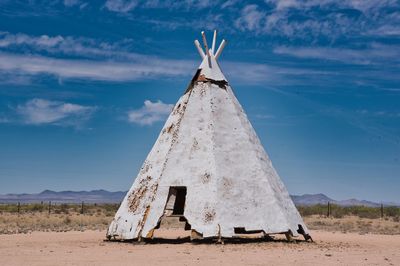 Traditional teepee on desert field against against a blue sky