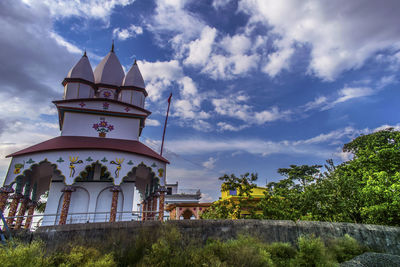 Low angle view of building by trees against sky