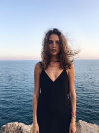 Portrait of young woman standing against sea