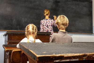 Rear view of teacher teaching students in classroom