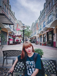 Portrait of beautiful woman against buildings in city