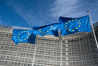 Low angle view of flags on building against blue sky