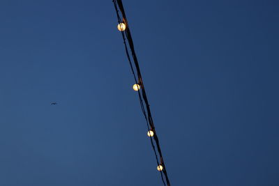 Low angle view of illuminated street light against clear blue sky