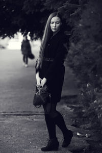 Full length portrait of young woman standing outdoors