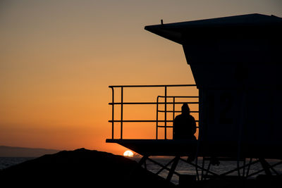 Silhouette people standing by sea against sky during sunset